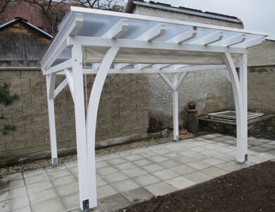 Zahradní pergola ke zdi domu s průhledným zastřešením pergoly